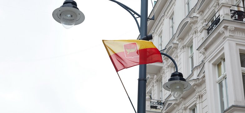 Żółto-czerwona flaga Łodzi na tle jednej z kamienic.